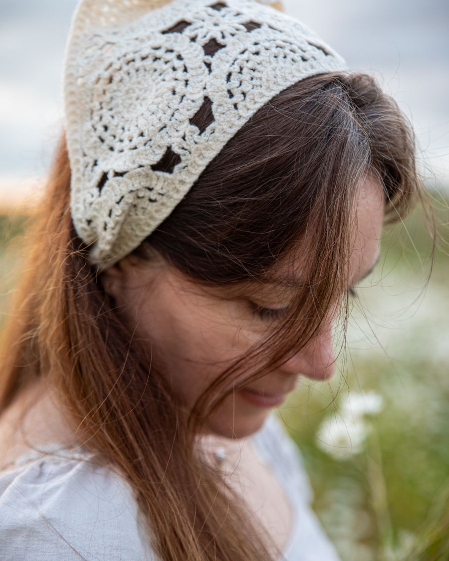 A woman wearing a natural cream crochet head covering outdoors